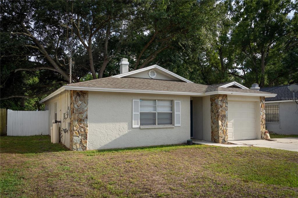 A single-story house with a stone-accented facade, a garage, and a white fence — 4703 SERENA DRIVE, TAMPA, FL