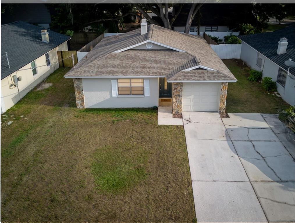 An aerial view of a single-story house with a stone facade, shingled roof, and driveway — 4703 SERENA DRIVE, TAMPA, FL