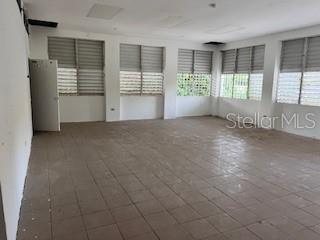 An empty room features light-colored floor tiles, white walls, and multiple windows with horizontal blinds — PR 1 Km 18.7 Int. SANCHEZ CAIMITO BAJO, SAN JUAN, PR