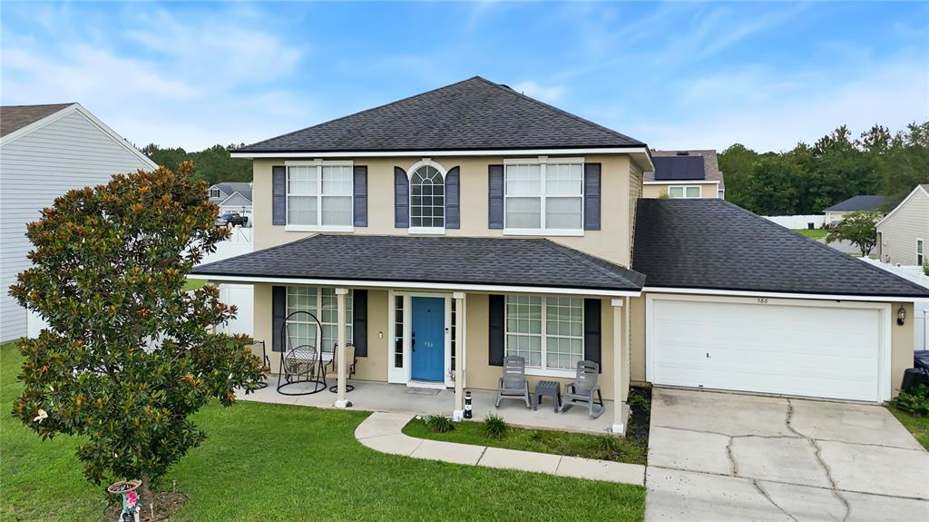 A two-story house with a blue front door, a covered porch, and an attached garage — 586 INDEPENDENCE DRIVE, MACCLENNY, FL