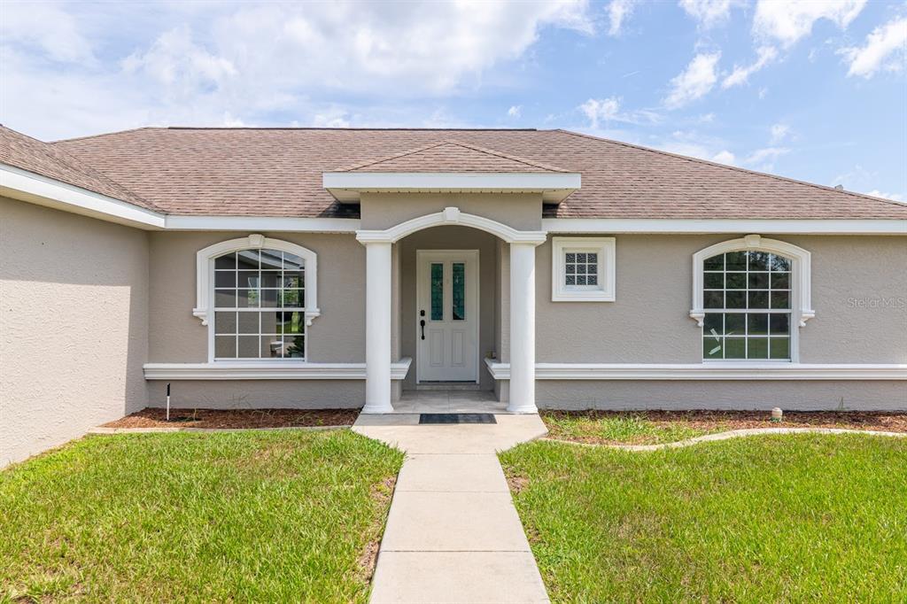 The front exterior of a single-story house features a white door, two columns, and arched windows — 14771 SW 27TH COURT ROAD, OCALA, FL