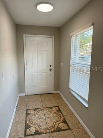 An entryway features beige tile flooring with a decorative inlay, a white door, and a window — 1631 SHERBOURNE STREET, WINTER GARDEN, FL