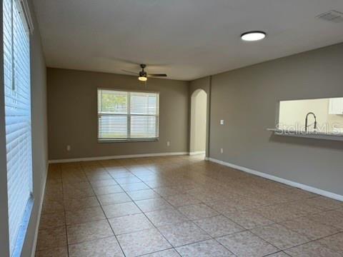 An open living area features tan tile flooring, a ceiling fan, and a kitchen pass-through window — 1631 SHERBOURNE STREET, WINTER GARDEN, FL