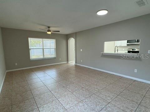 An open living area features tile flooring, a ceiling fan, and a kitchen pass-through window — 1631 SHERBOURNE STREET, WINTER GARDEN, FL