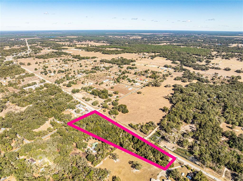 An aerial view shows a rectangular plot of land outlined in pink amidst rural terrain — 000 S HWY 25, WEIRSDALE, FL