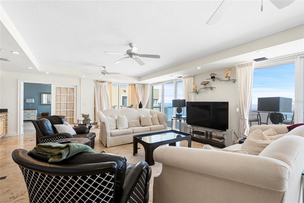A living room features two sofas, two leather armchairs, a coffee table, and ocean views — 1350 GULF BOULEVARD UNIT 901, CLEARWATER BEACH, FL