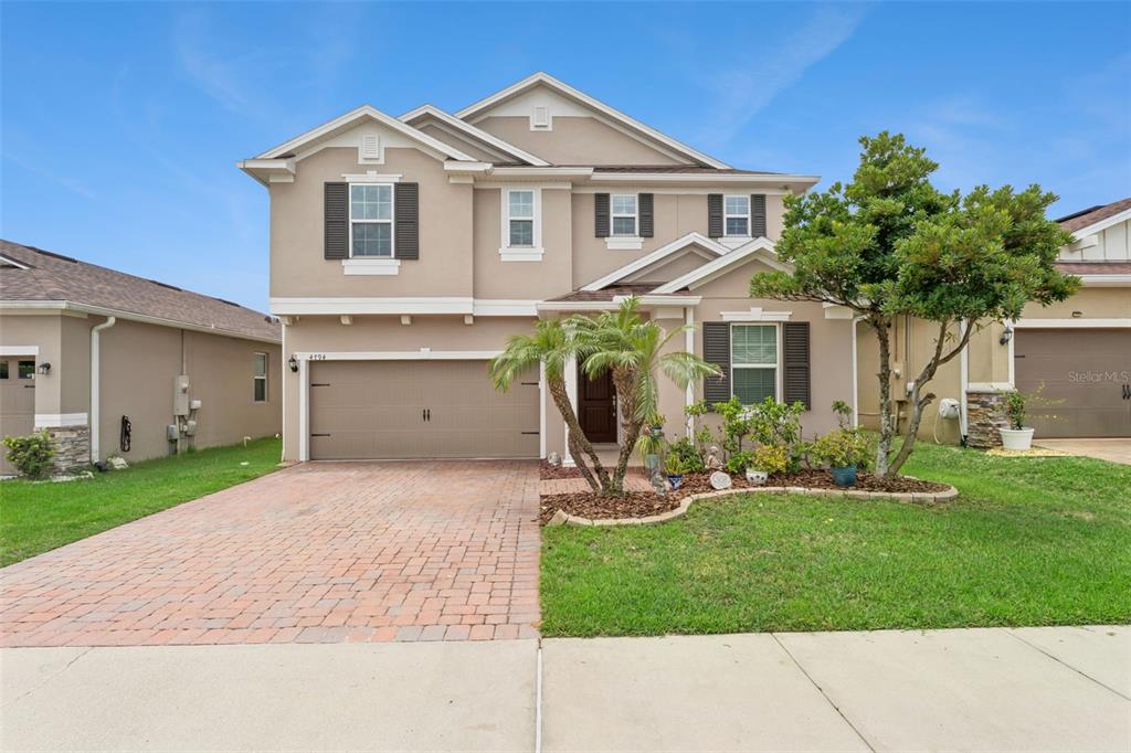 A two-story suburban house features a tan stucco exterior, a brick driveway, and a garage — 4794 GRASSENDALE TERRACE, SANFORD, FL