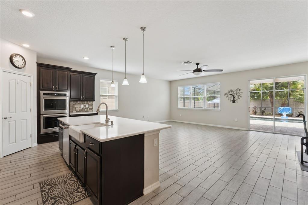 A kitchen with dark cabinets, a white island, and tile floors opens to a living area — 4794 GRASSENDALE TERRACE, SANFORD, FL