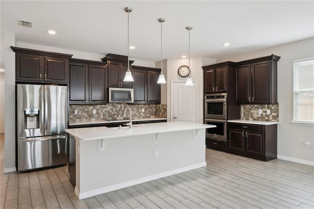A kitchen featuring dark wood cabinets, stainless steel appliances, a white island, and tiled floors — 4794 GRASSENDALE TERRACE, SANFORD, FL