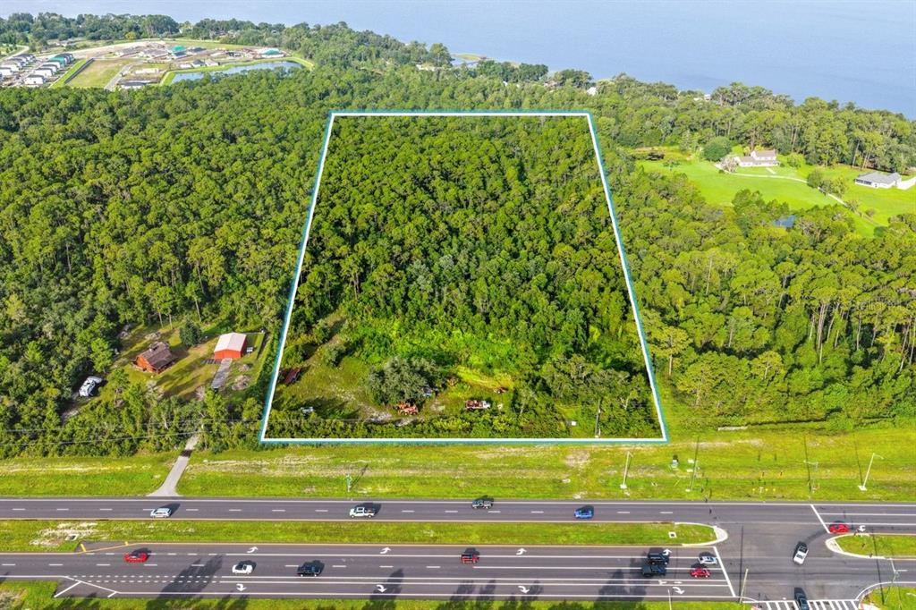 An aerial view shows a rectangular, wooded plot of land bordering a multi-lane highway — 0 E IRLO BRONSON MEMORIAL HIGHWAY, ST CLOUD, FL