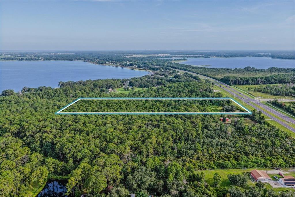 An aerial view shows a rectangular plot of land outlined in blue near a lake — 0 E IRLO BRONSON MEMORIAL HIGHWAY, ST CLOUD, FL
