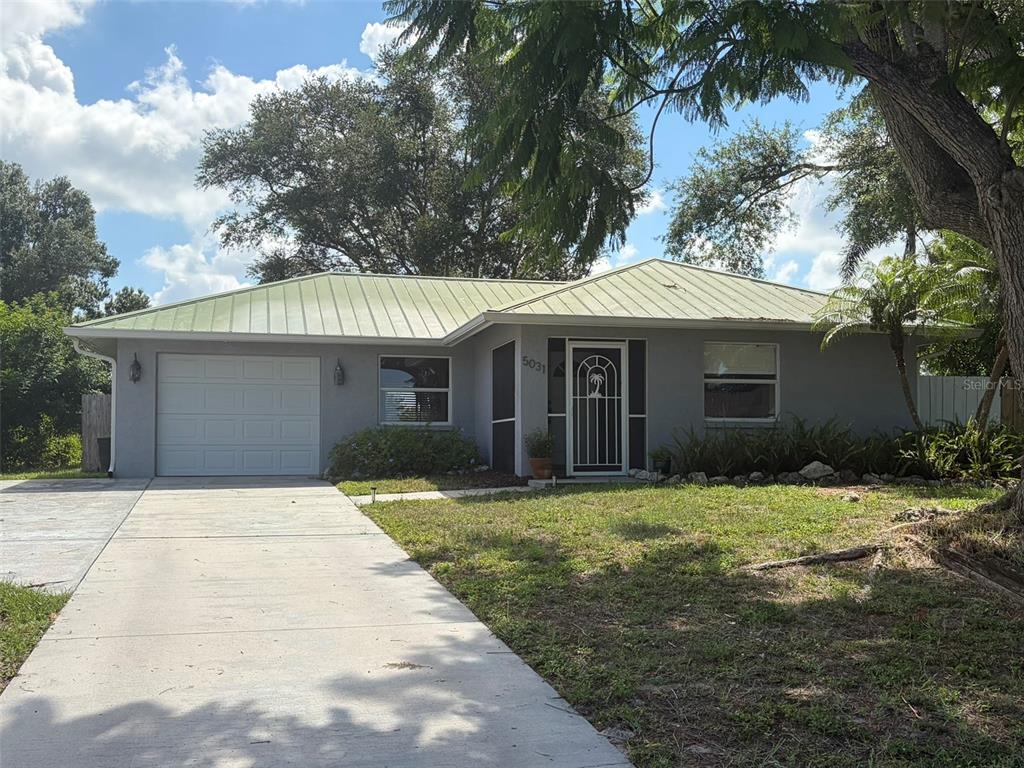 A single-story gray house with a metal roof and a concrete driveway — 5031 PRESTON WAY, SARASOTA, FL