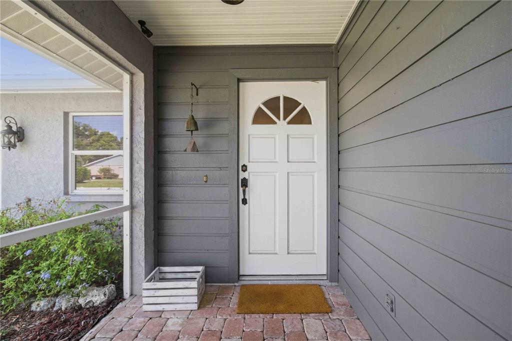 A white front door with a semi-circular window sits on a brick porch — 5031 PRESTON WAY, SARASOTA, FL