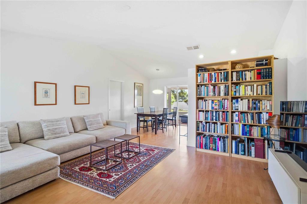 A living and dining area with light wood floors, a sectional sofa, and large bookshelves — 5031 PRESTON WAY, SARASOTA, FL