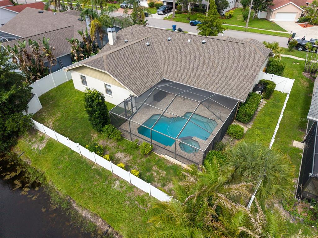 An aerial view of a house with a screened-in pool and a fenced backyard — 447 WHISPERING LAKES BOULEVARD, TARPON SPRINGS, FL