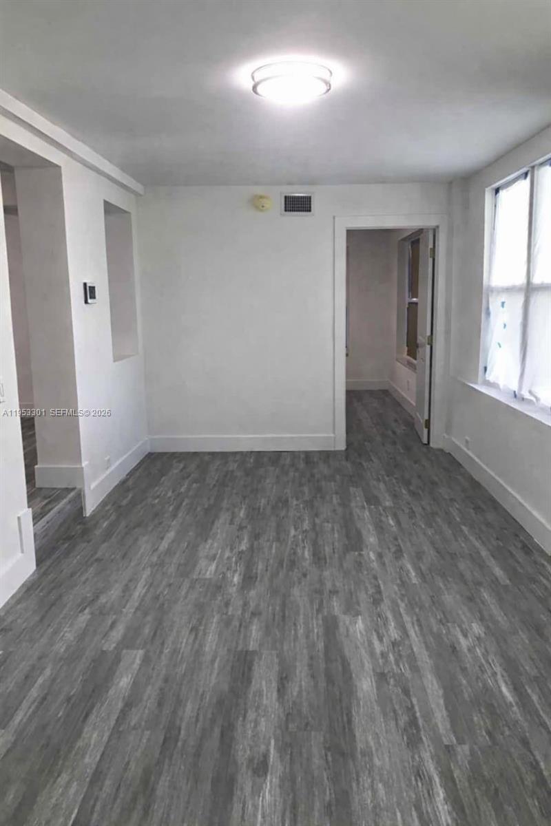 A room with white walls, gray wood-look flooring, and a doorway leading to another room — 1920 Rutland St, Opa-Locka FL 33054, OPA-LOCKA, FL