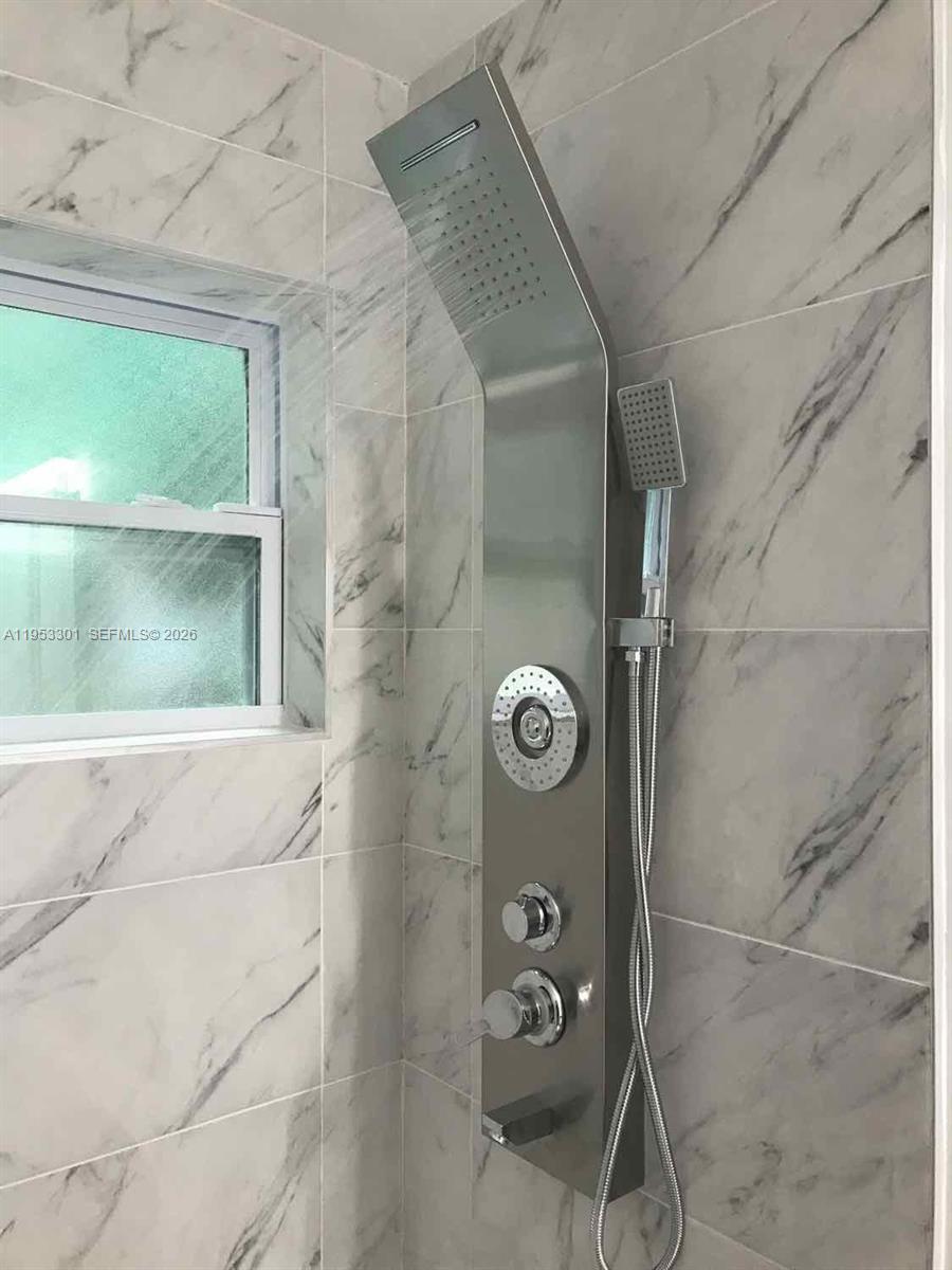 A modern stainless steel shower panel is mounted on a marble-tiled shower wall — 1920 Rutland St, Opa-Locka FL 33054, OPA-LOCKA, FL