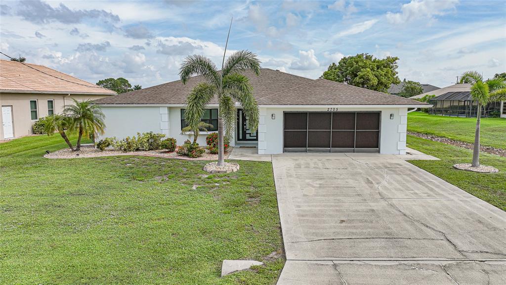 A single-story house with a white exterior, a two-car garage, and a palm tree — 2705 MAURITANIA ROAD, PUNTA GORDA, FL