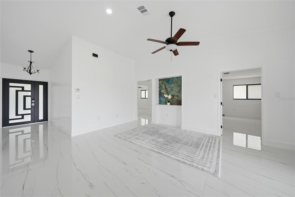 A bright, open-concept living area features white marble-look tile flooring and a ceiling fan — 2705 MAURITANIA ROAD, PUNTA GORDA, FL