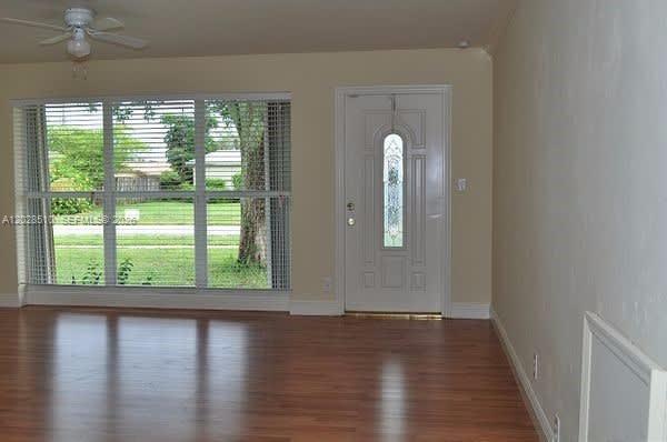 A living room with wood-look flooring, a large window, and a white front door — FORT LAUDERDALE, FL