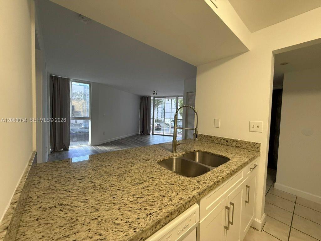 A kitchen with granite countertops and a double sink overlooks a living area — 6955 NW 186th St # F209, Hialeah FL 33015, HIALEAH, FL