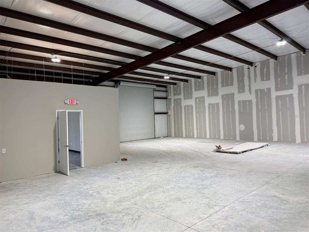 An interior view of a warehouse space with concrete floors, exposed beams, and unfinished drywall — 5741 S PINE AVENUE, OCALA, FL