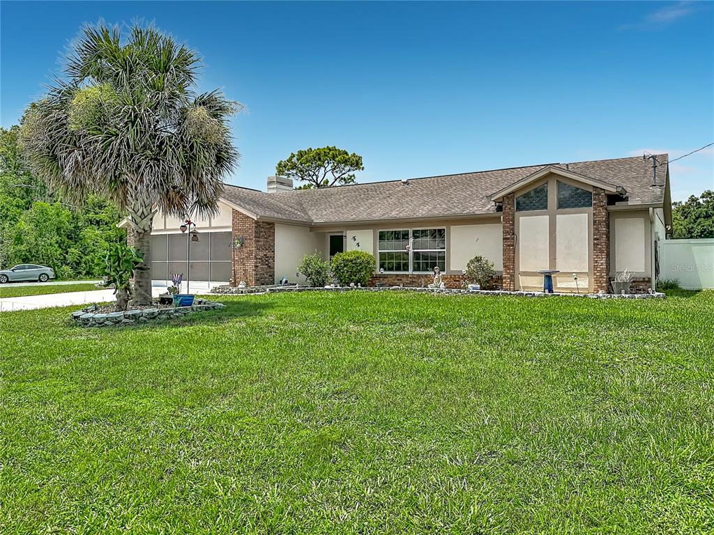 A single-story house with a palm tree, brick accents, and a large front lawn — 10433 DUNKIRK ROAD, SPRING HILL, FL