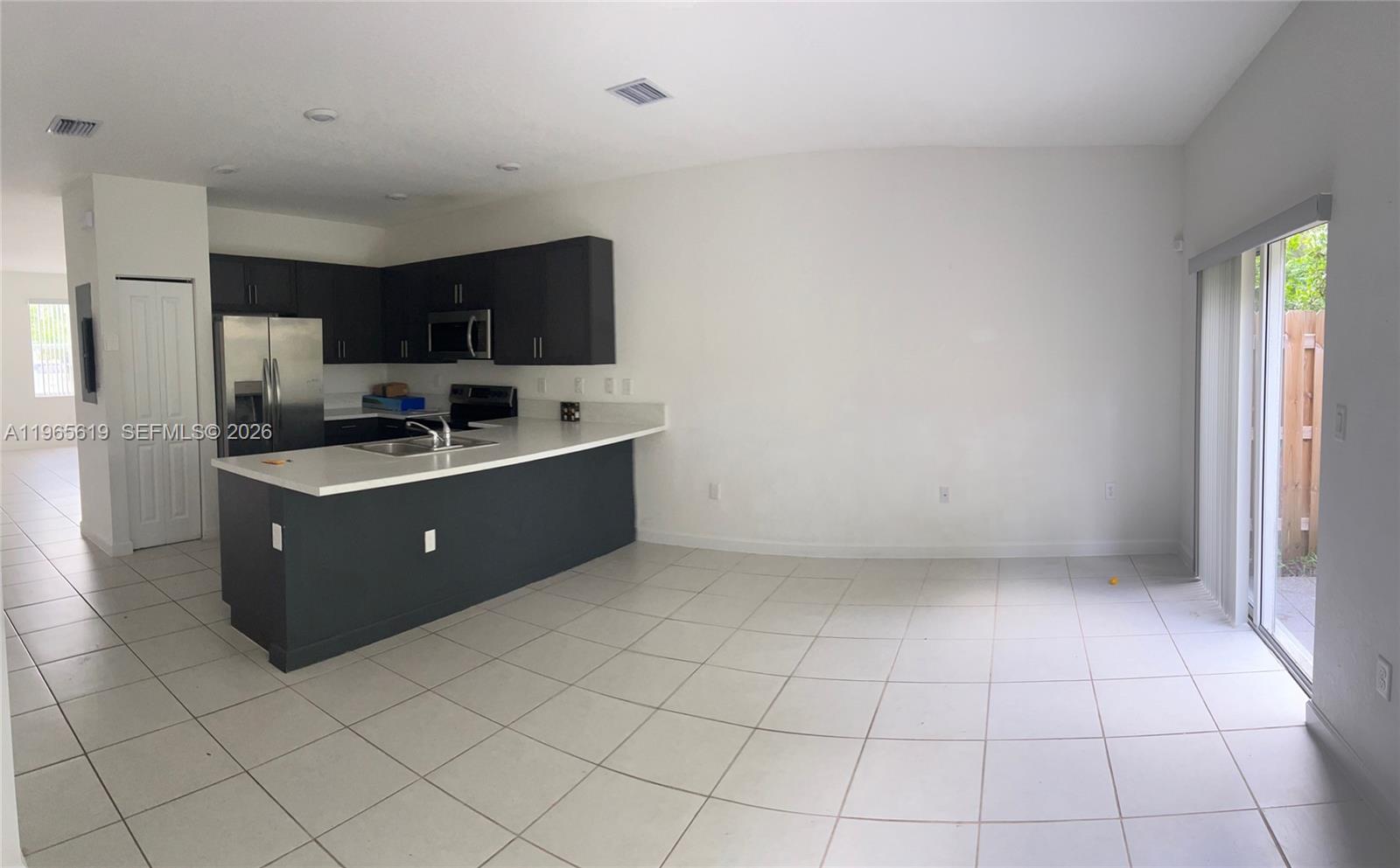 A kitchen with dark cabinets and a white countertop opens into a tiled living area — 2672 SE 19th St, Homestead FL 33035, HOMESTEAD, FL