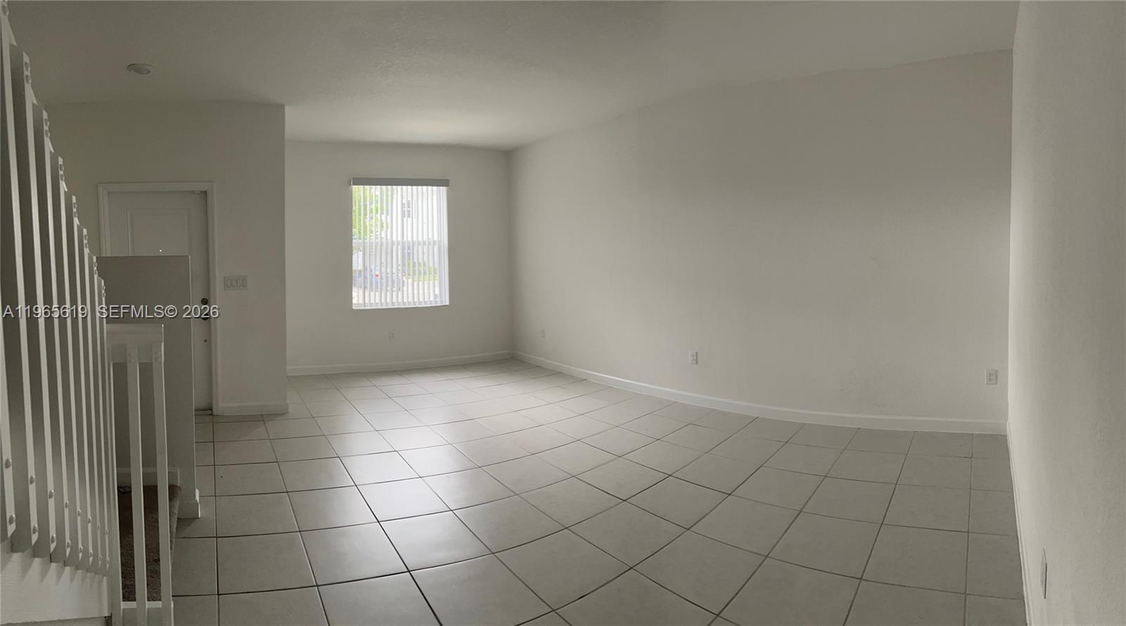 An empty room features white walls, light-colored floor tiles, and a window with vertical blinds — 2672 SE 19th St, Homestead FL 33035, HOMESTEAD, FL