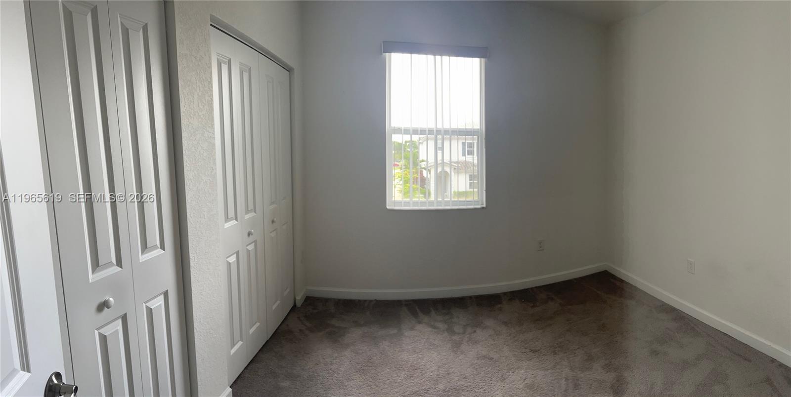 An empty bedroom features gray carpeting, white walls, a closet, and a single window — 2672 SE 19th St, Homestead FL 33035, HOMESTEAD, FL