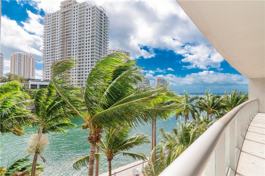 A balcony view overlooking a waterway, palm trees, and high-rise buildings under a cloudy sky — 465 Brickell Avenue # 419, Miami FL 33131, MIAMI, FL