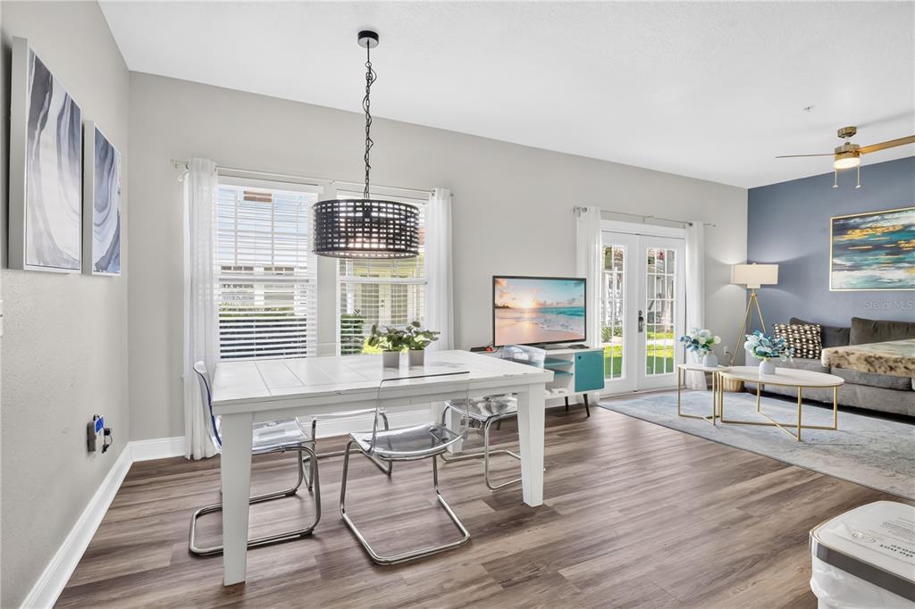 A dining area with a white table and clear chairs sits beside a living room — 5352 DIPLOMAT COURT UNIT 108, KISSIMMEE, FL