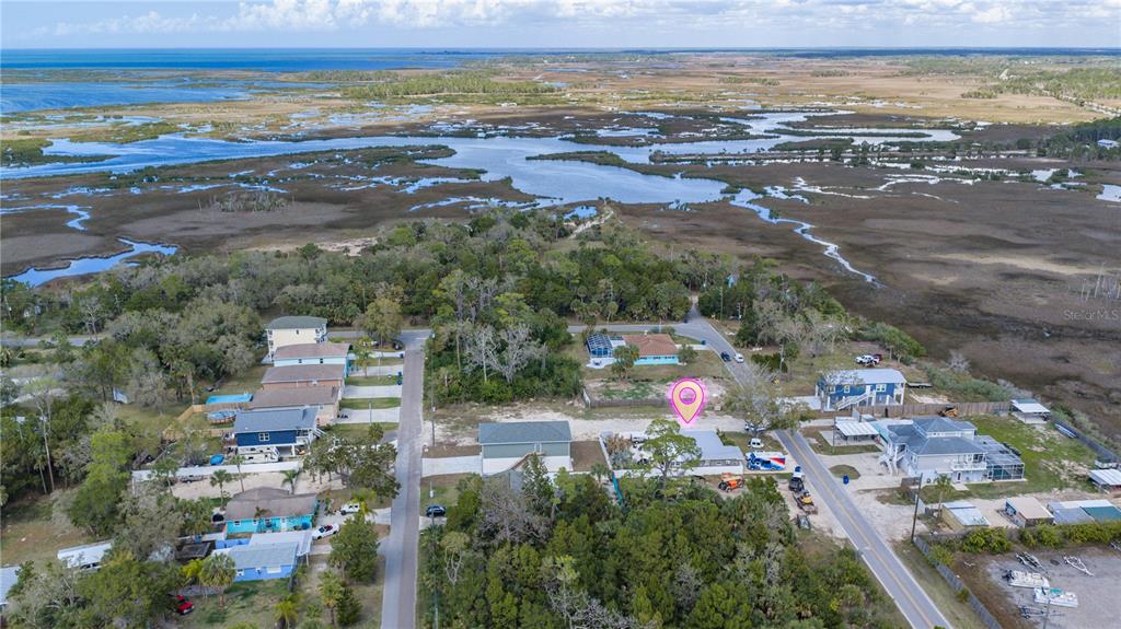 An aerial view shows a coastal neighborhood with houses, trees, and surrounding marshland — MAPLEWOOD DRIVE, HERNANDO BEACH, FL