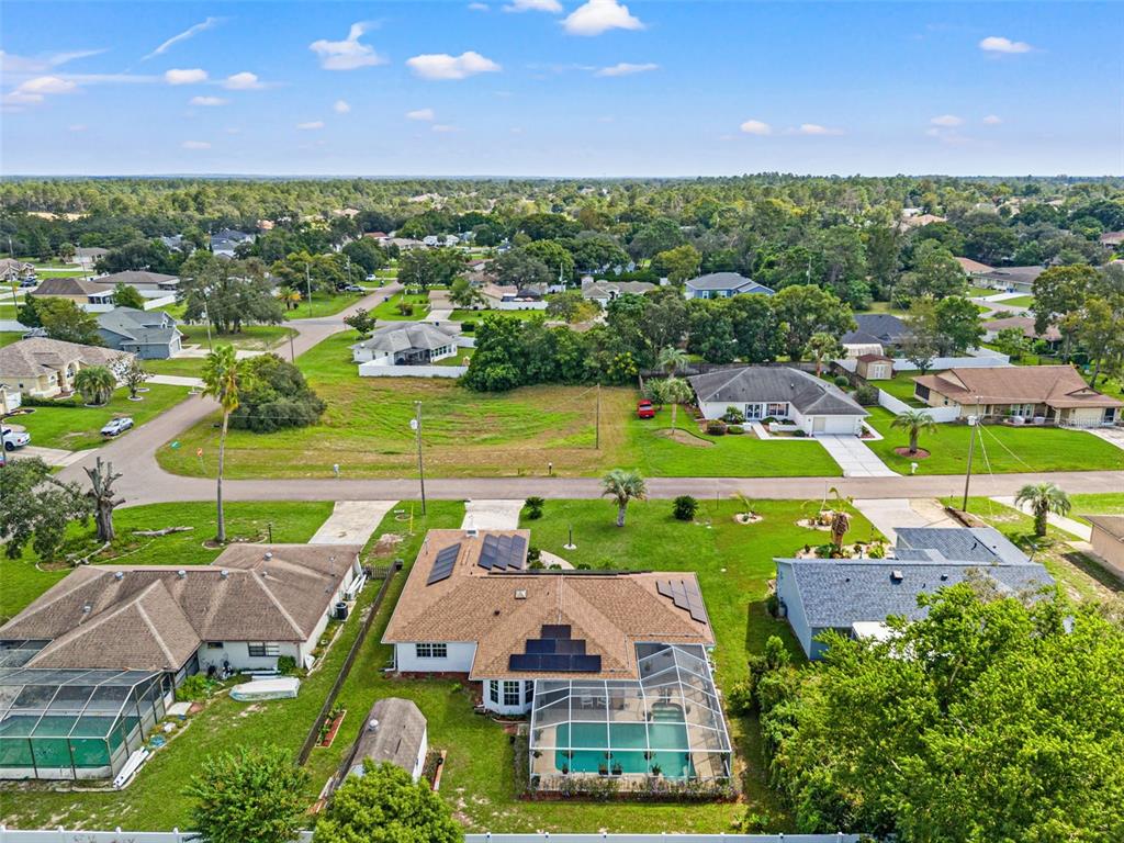 An aerial view shows a residential neighborhood with houses, a swimming pool, and vacant lots — 3077 ARDENWOOD DRIVE, SPRING HILL, FL