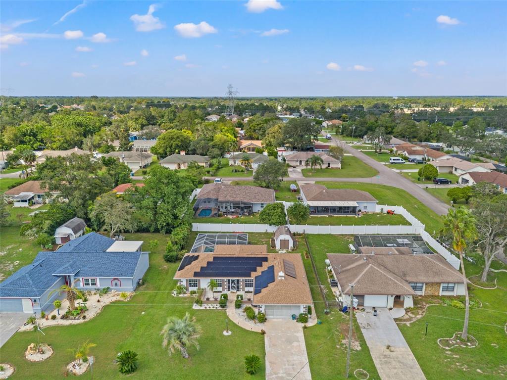 An aerial view of a suburban neighborhood featuring houses with solar panels and screened pools — 3077 ARDENWOOD DRIVE, SPRING HILL, FL