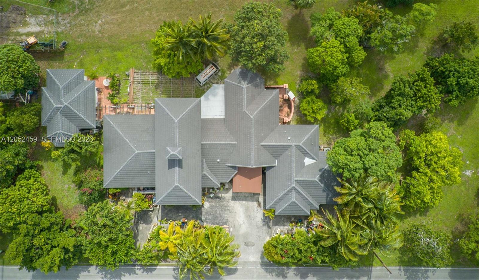 An aerial view shows a large house with a gray tile roof and surrounding trees — 5400 Palm Tree Rd, Plantation FL 33317, PLANTATION, FL