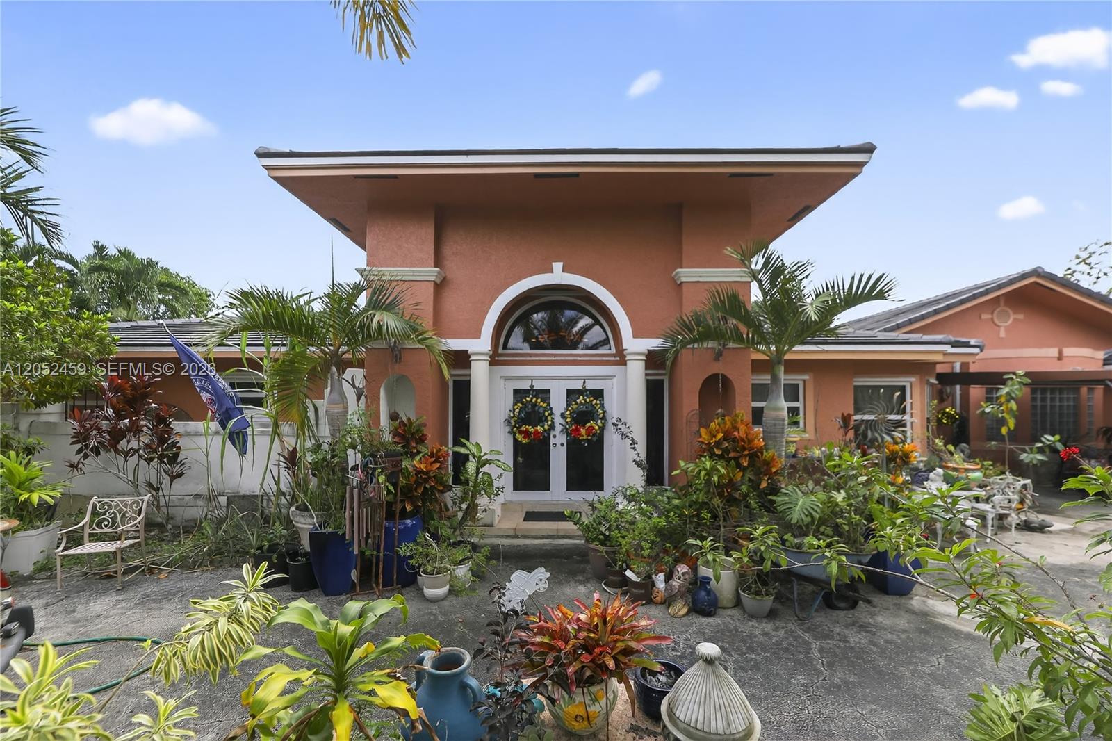 The exterior of a peach-colored house features a prominent arched entryway with double doors — 5400 Palm Tree Rd, Plantation FL 33317, PLANTATION, FL