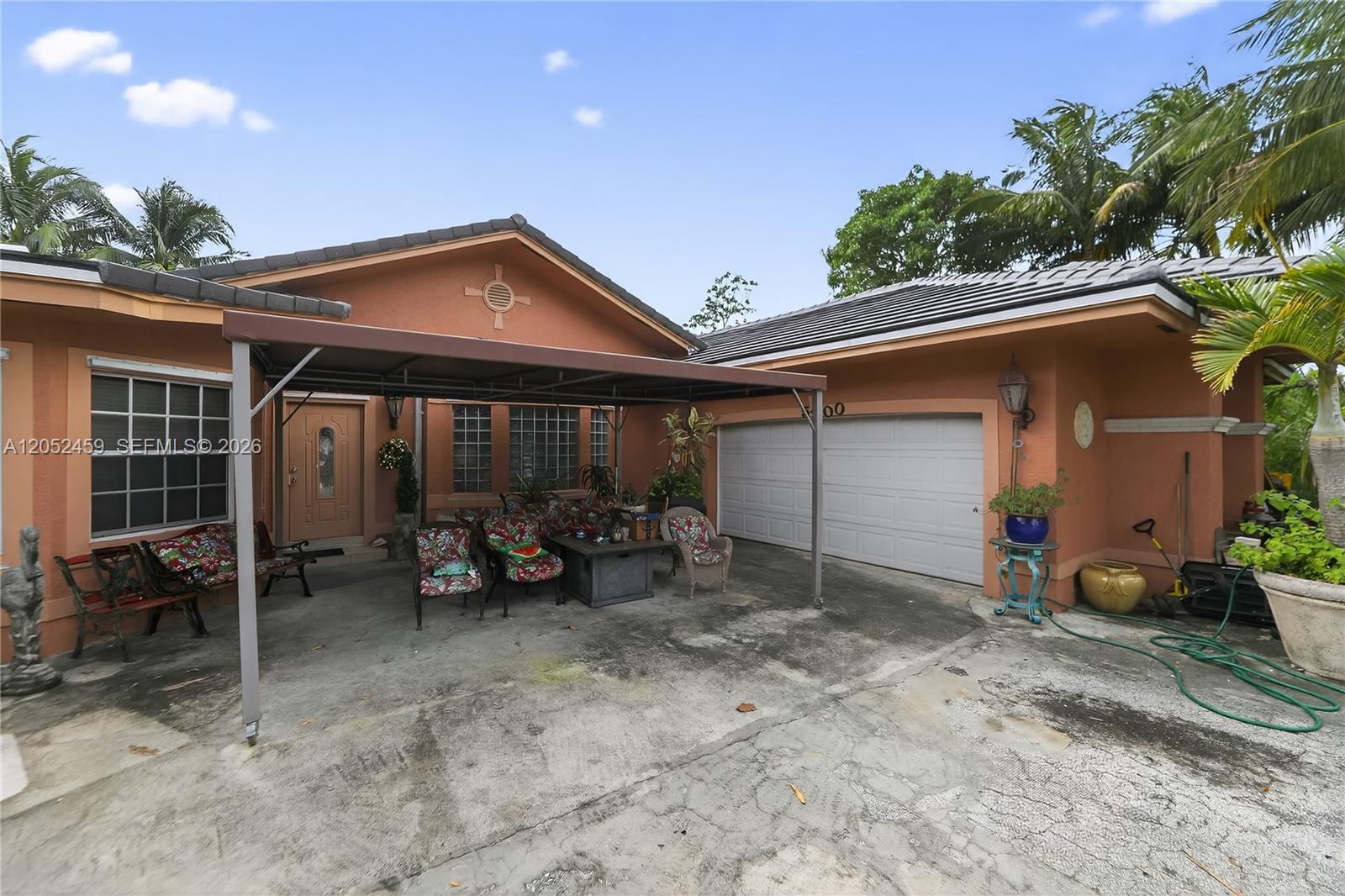 The exterior of a single-story house features a covered patio, a two-car garage, and landscaping — 5400 Palm Tree Rd, Plantation FL 33317, PLANTATION, FL