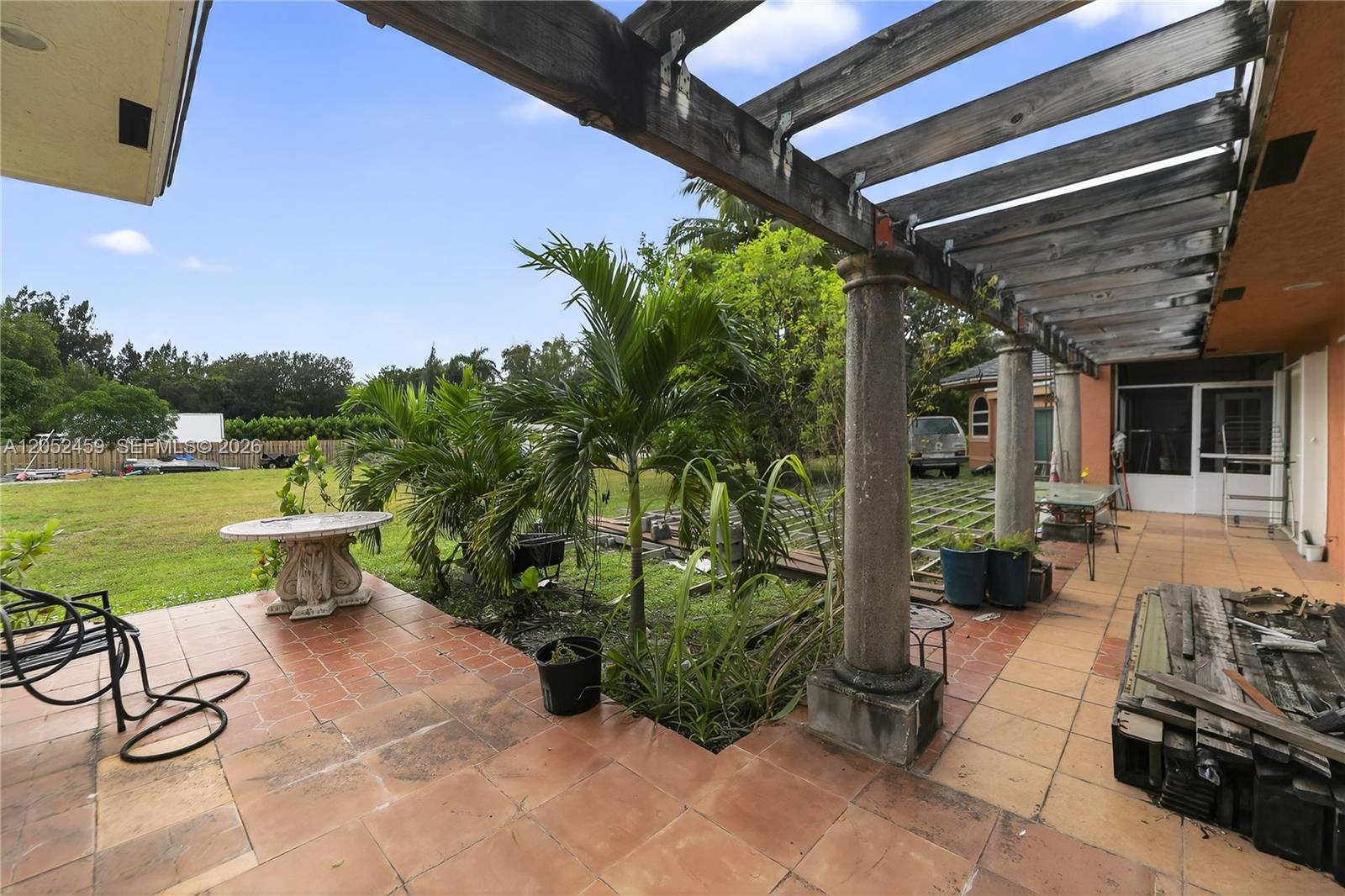 A patio features a wooden pergola, stone columns, and tiled flooring overlooking a grassy yard — 5400 Palm Tree Rd, Plantation FL 33317, PLANTATION, FL