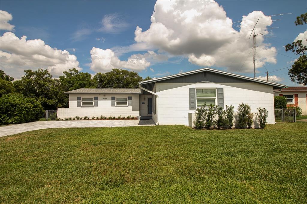 A white, single-story house with a gray roof and shutters sits behind a green lawn — 3019 TAMPICO DRIVE, ORLANDO, FL