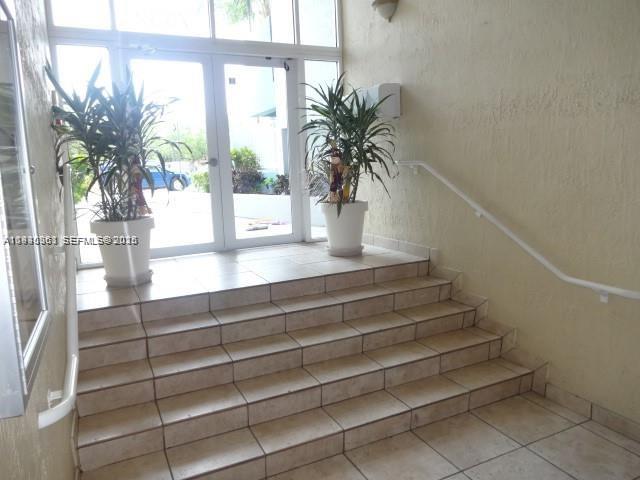 A tiled staircase leads to a glass-paned double door flanked by two potted plants — 7832 Collins Ave # 403, Miami Beach FL 33141, MIAMI BEACH, FL