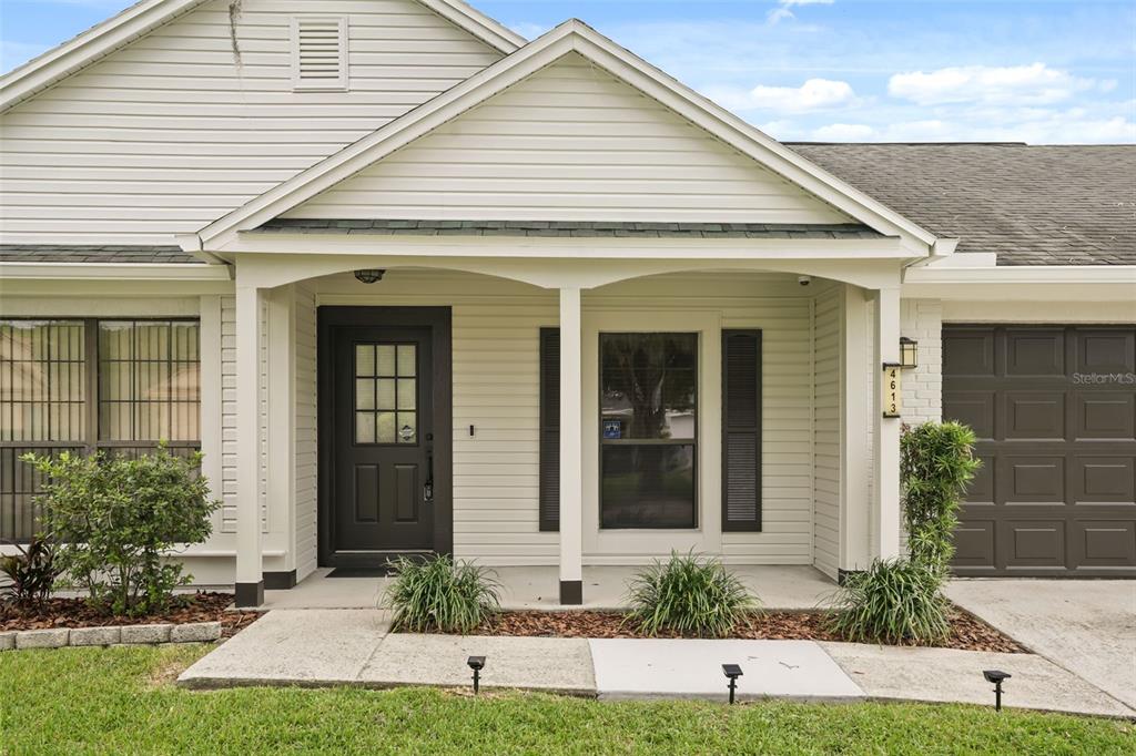 The exterior of a house features a covered porch, a dark front door, and a garage — 4613 FLATWOOD LANE, ORLANDO, FL