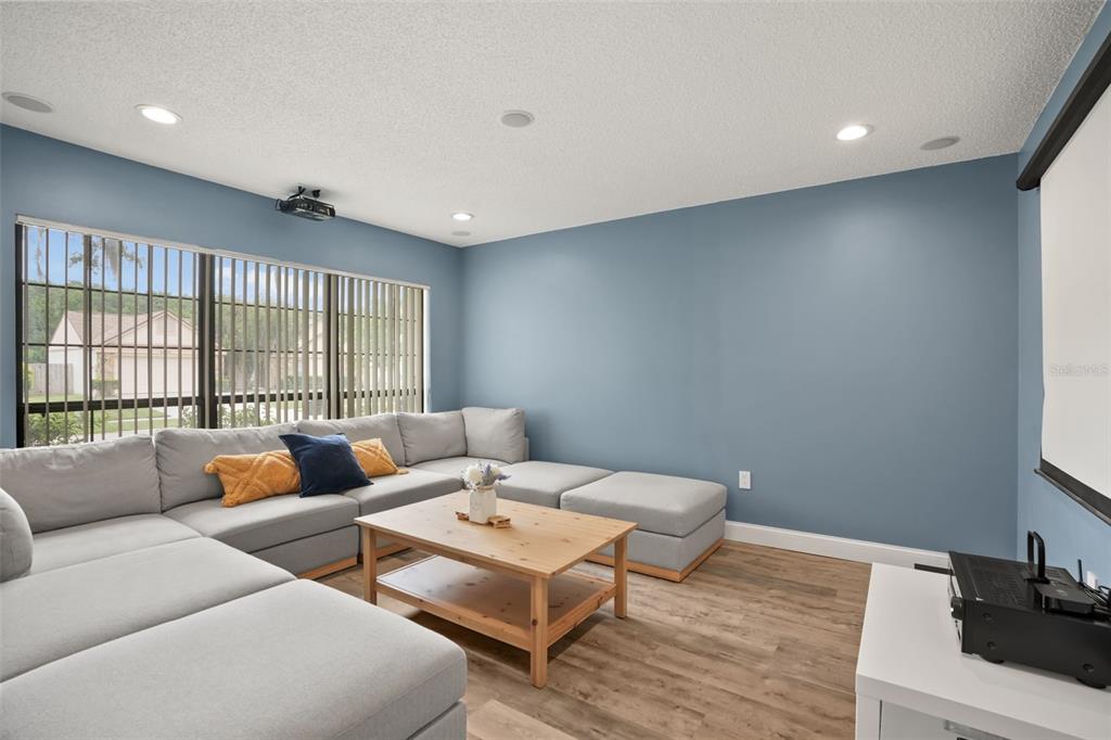A living room features a large gray sectional sofa, a wooden coffee table, and a projector — 4613 FLATWOOD LANE, ORLANDO, FL