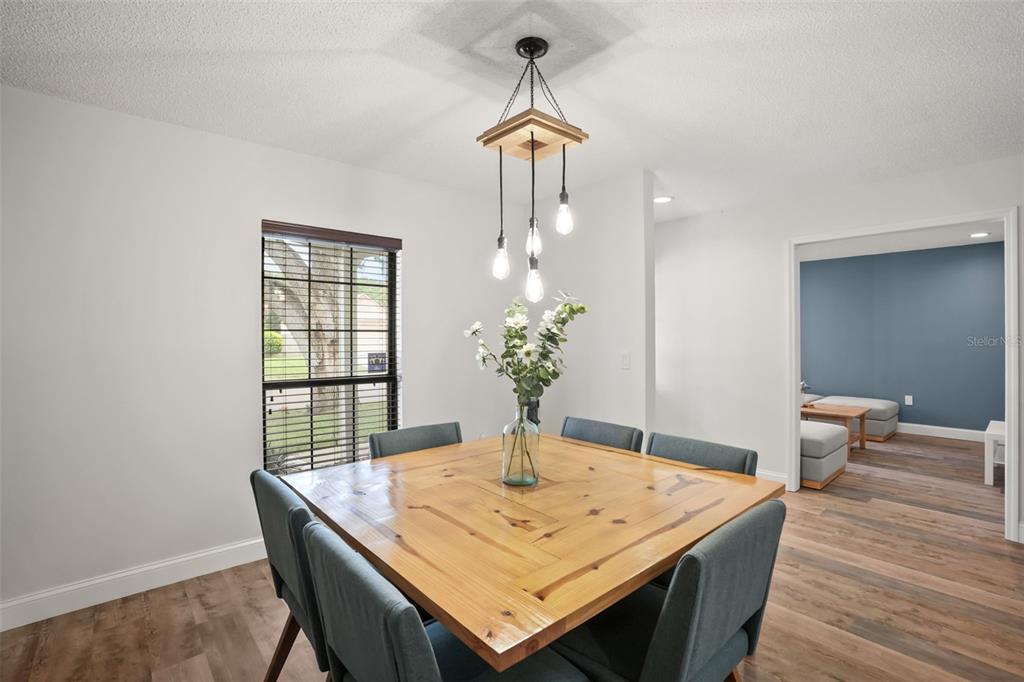 A dining room features a square wooden table, blue chairs, and a modern pendant light — 4613 FLATWOOD LANE, ORLANDO, FL
