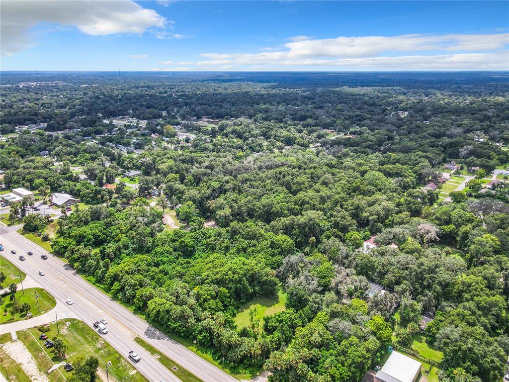 An aerial view shows a wooded lot adjacent to a multi-lane road and residential area — 1351 N VOLUSIA AVENUE, ORANGE CITY, FL