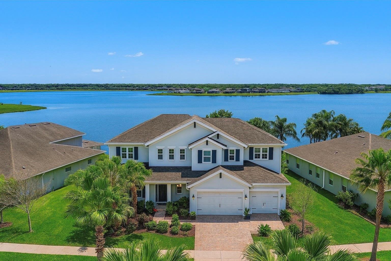 An aerial view of a two-story suburban house with a lake in the background — 11333 Lake Lucaya Drive, FL 33579, FL