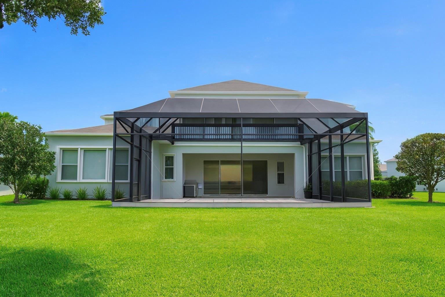 The exterior rear view of a house features a large screened-in patio and balcony — 11333 Lake Lucaya Drive, FL 33579, FL