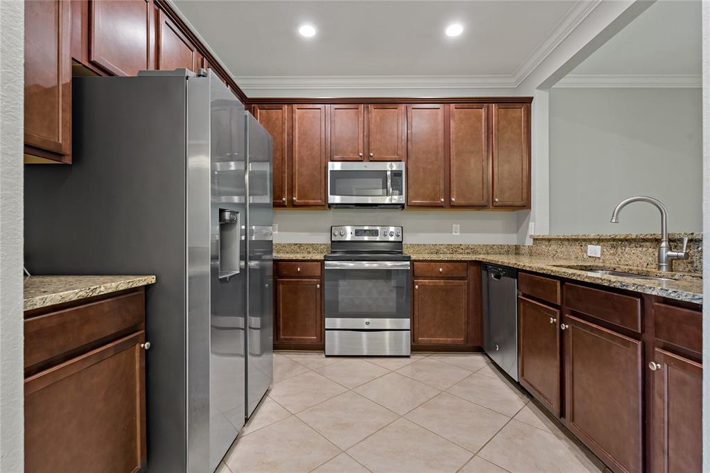 A kitchen features dark wood cabinets, stainless steel appliances, and granite countertops — 7275 KETCH PLACE, BRADENTON, FL