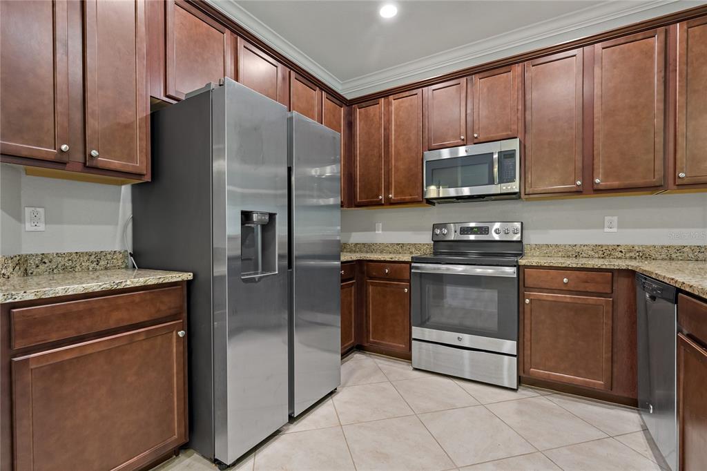 A kitchen features dark wood cabinets, stainless steel appliances, and granite countertops — 7275 KETCH PLACE, BRADENTON, FL