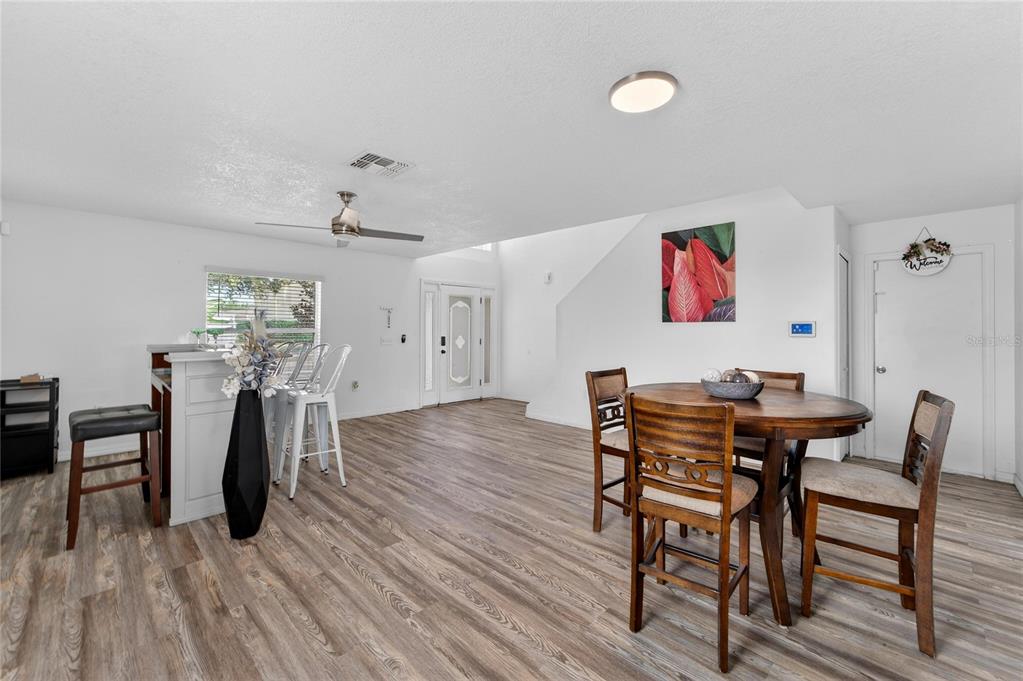 A dining area and breakfast bar feature wood-look flooring and a ceiling fan — 10325 FROG POND DRIVE, RIVERVIEW, FL